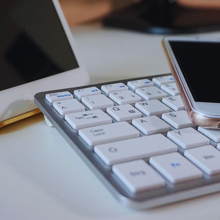 Eine weiße Tastatur mit einem Smartphone und einem Tablet auf einem Tisch.
